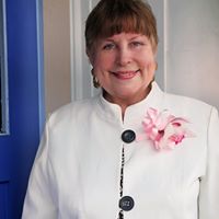 Rev. Frances Lorenz in white suit with pink lapel flower